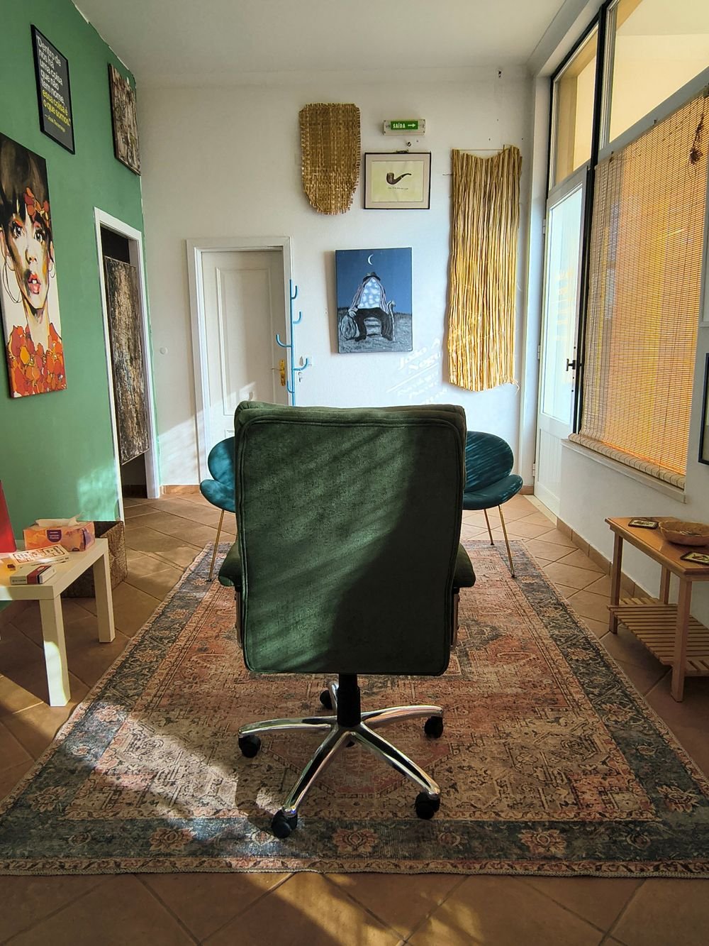 Sala de consulta: um cadeirão verde frente a duas cadeiras azuis, sobre um tapete